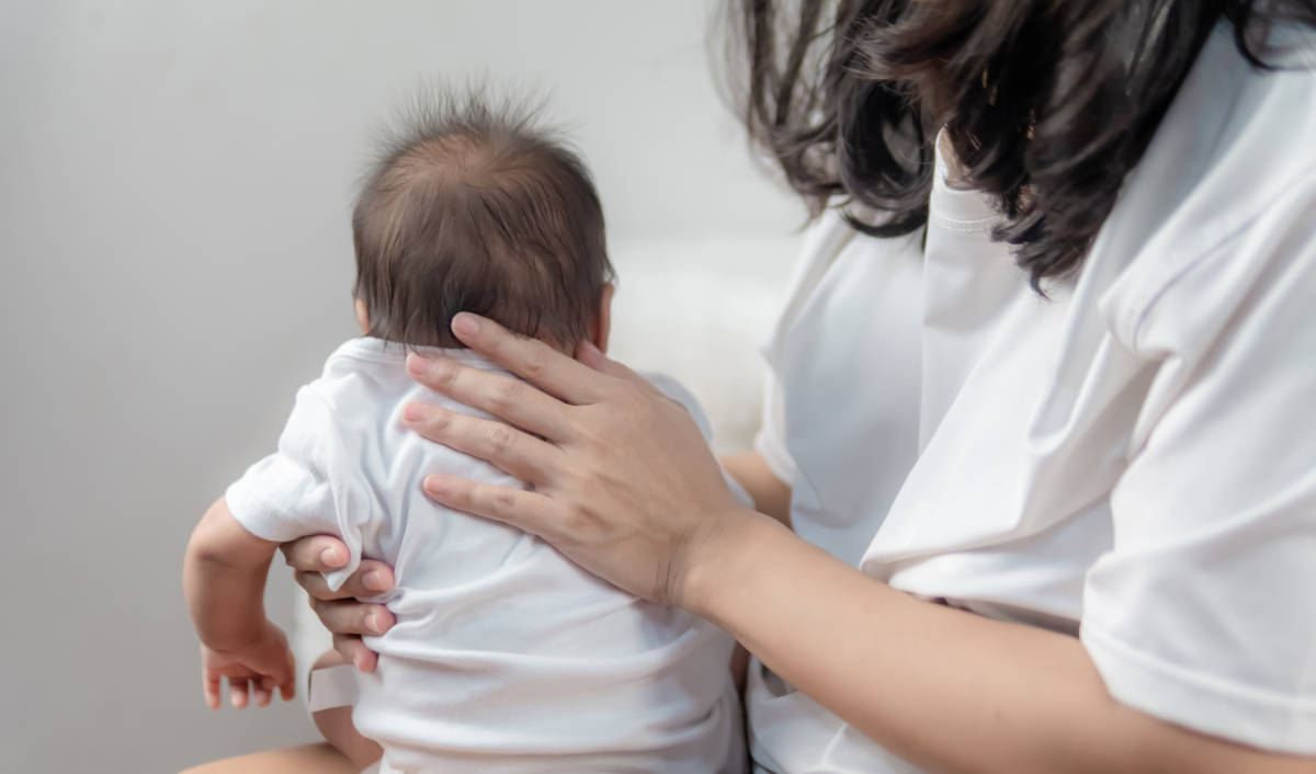 Ibu sedang menyendawakan bayi untuk menghentikan cegukan