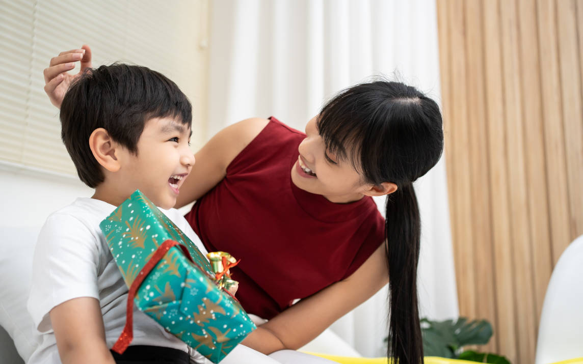  Seorang ibu sedang memberikan kado untuk anak laki-laki