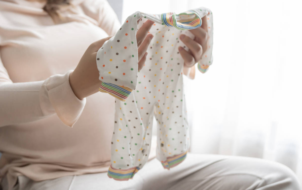 Seorang ibu sedang memegang baju bayi