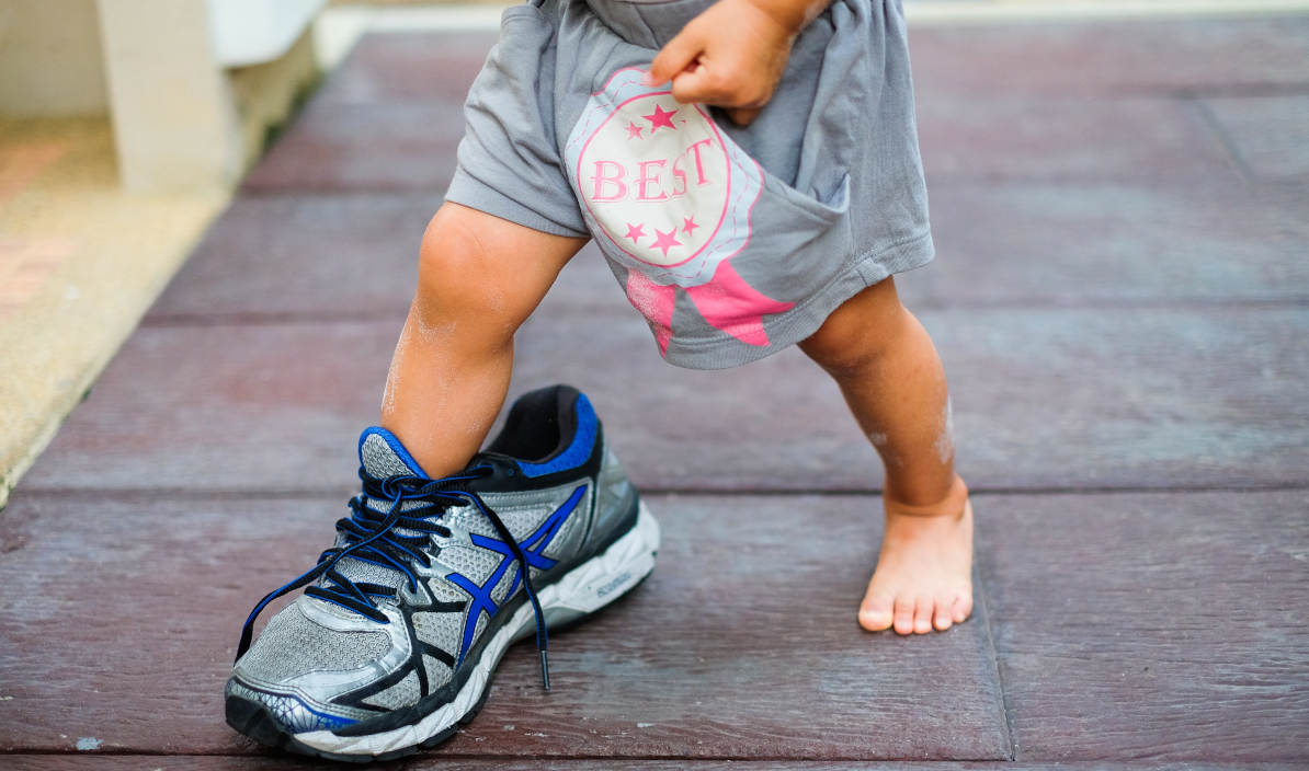 Seorang anak memakai sepatu dewasa 