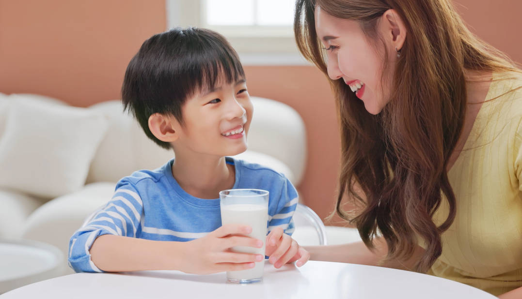 Seorang anak sedang minum susu didampingi ibu