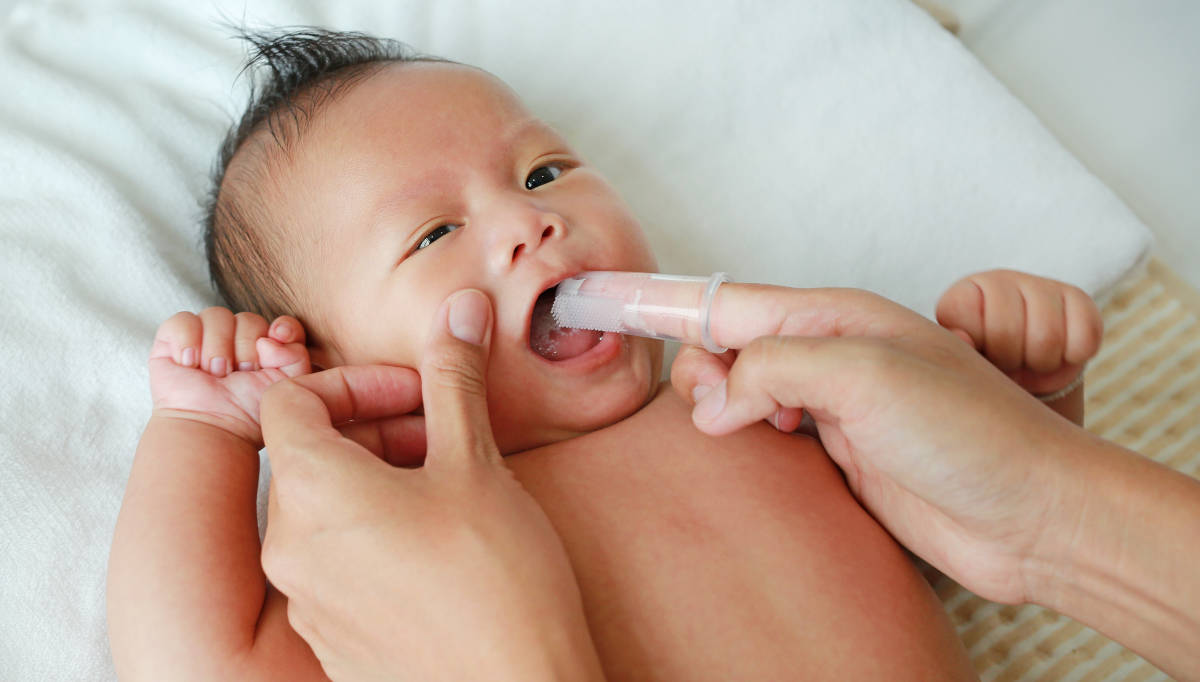 Bayi sedang dibersihkan mulutnya 